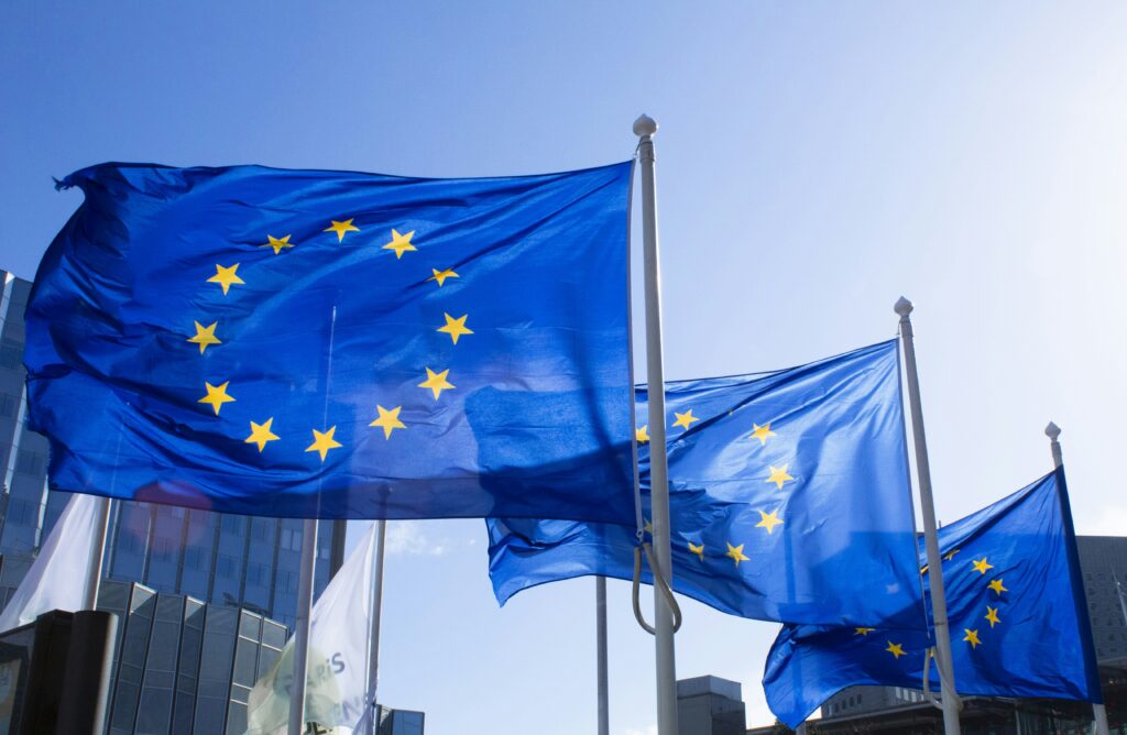 EU-flaggor blåser i vinden framför blå himmel.