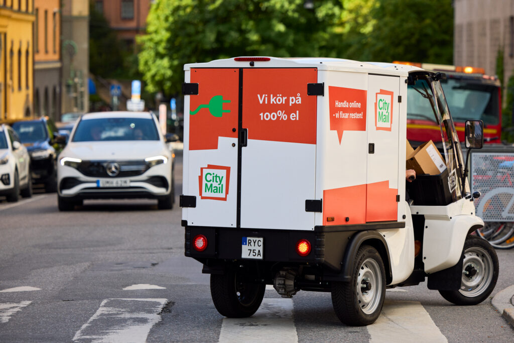 En mindre budbil i stadsmiljö med texten "Vi kör på 100% el"